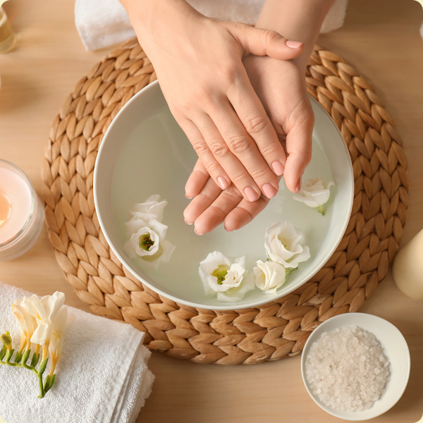 Hand soaking in a spa bowl with flowers and natural salts