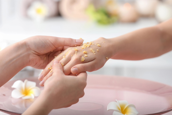 Young woman undergoing cosmetic procedures for hands in spa salon